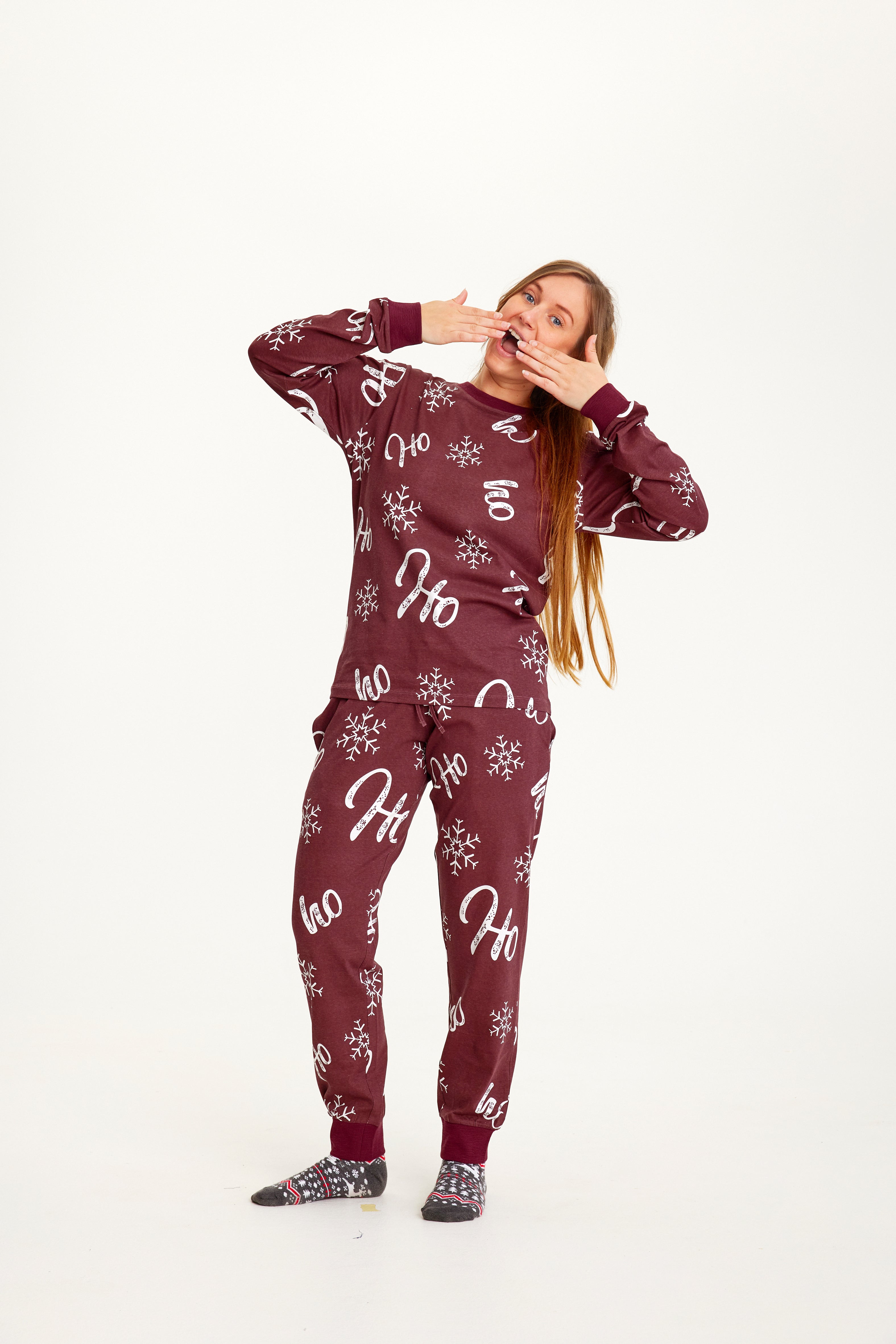 En gjespende kvinne iført rød julepyjamas med julemønster.